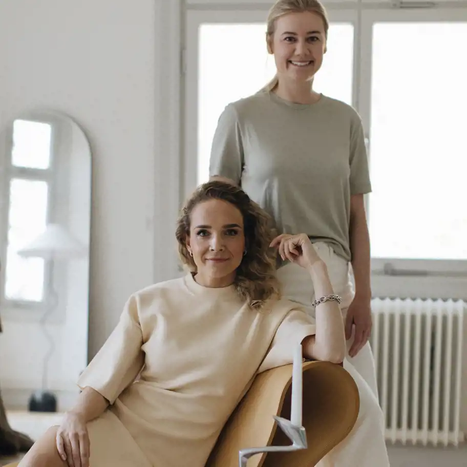 Vendela Wikman sitter i en fåtölj och Linnea Markmeyer står bakom henne.